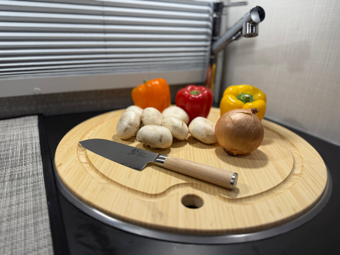 GripTurf Bamboo Prep Pro cutting board and sink cover shown in use with vegetables and a kitchen knife.