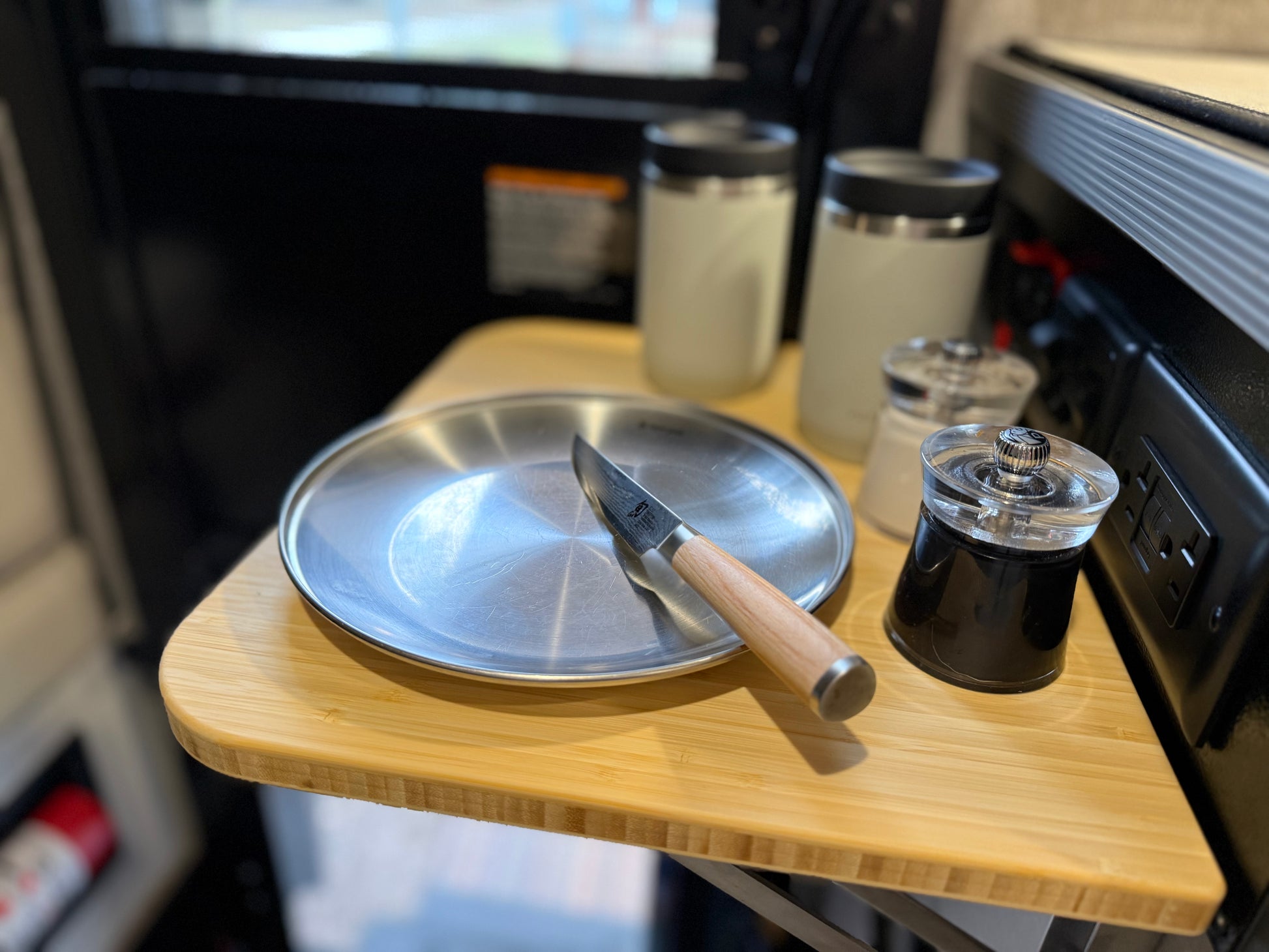 GripTurf Natural Bamboo Folding Countertop Extension in the Winnebago EKKO kitchen, shown in use with cups, plate, knife, and shakers
