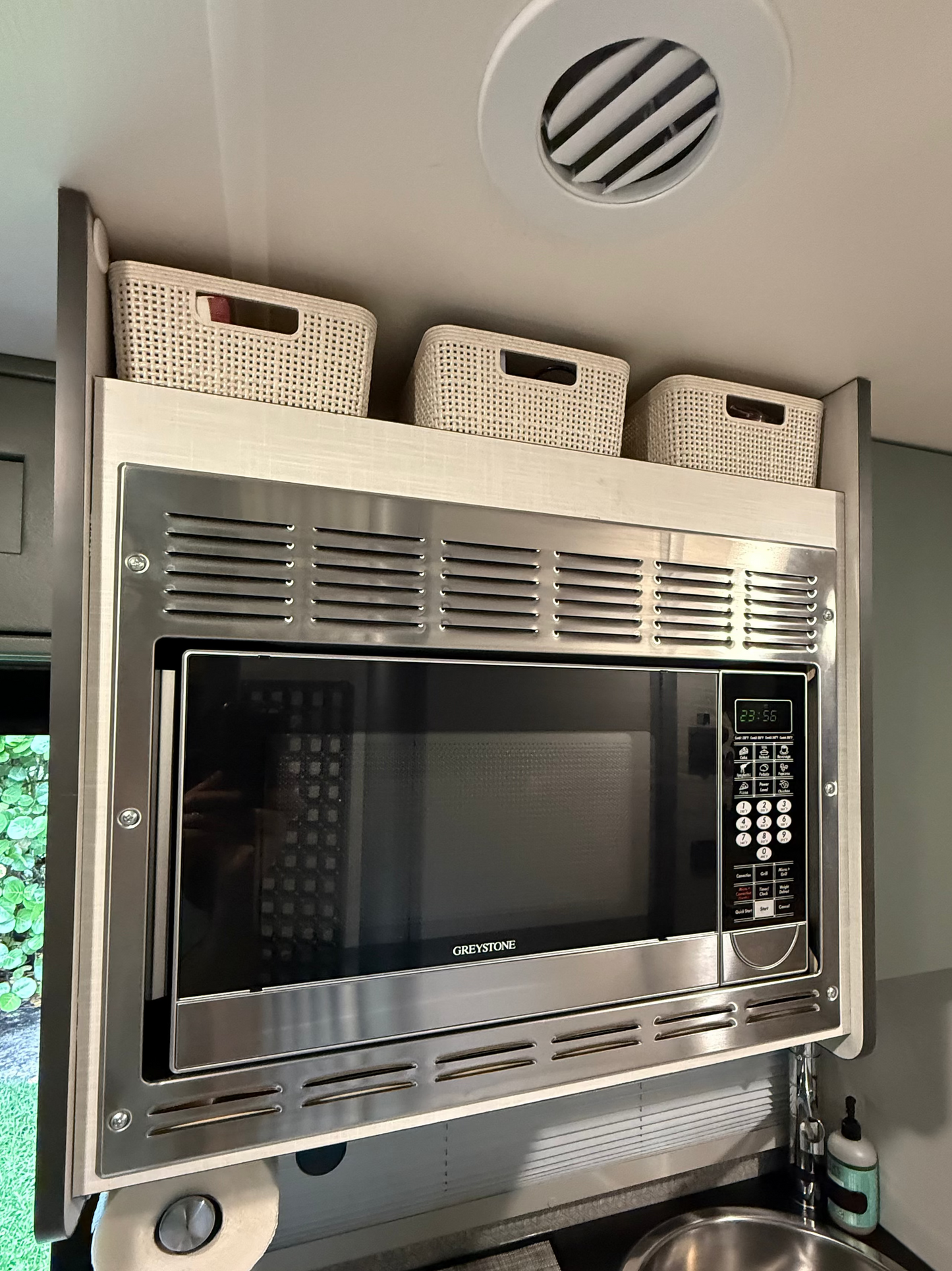 GripTurf cream RV storage baskets above the microwave in the Winnebago EKKO for organized kitchen storage